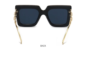 Detail showing high-gloss black square frame sunglasses with golden chain link temples