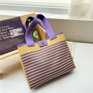 Macro shot of striped knit tote bag with purple wide strap and button detail on a ledge