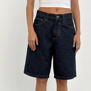 Close-up of high-waist dark blue denim shorts with yellow contrast stitching detail