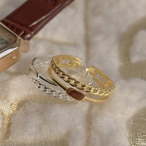 Close-up of gold and silver double-layered chain rings on beige textured fabric