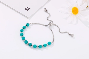 Détail d'un bracelet en acier inoxydable avec perles turquoise et chaîne coulissante