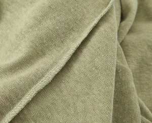 Macro shot of light green linen blend knit fabric texture and edge stitching detail