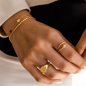 Detailed view of snake-shaped gold ring and starburst signet ring worn by a model