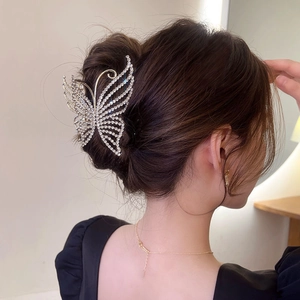 Detail view of a silver butterfly hair claw with rhinestones on a female model's hair