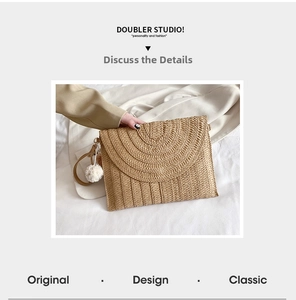 Detail of hand-woven straw clutch featuring a soft white pompom and secure wrist strap