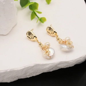 Macro shot of 18k gold plated baroque pearl earrings with crystals on stone background