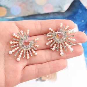 Detail of sunburst earrings featuring white pearls and rhinestones on gold alloy base