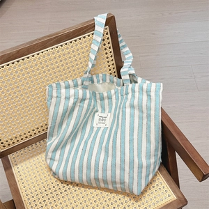 Blue and white striped canvas tote bag with a floral LOVE patch hanging on a wooden chair