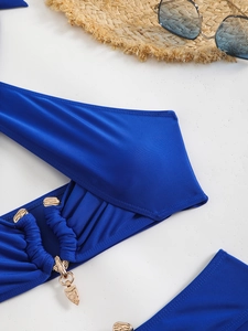 Detail of bright blue ruched bikini fabric with elegant gold metal hardware and pendant
