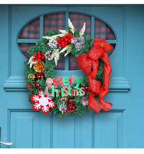 Detail of a Christmas wreath with pine needles, red velvet bow, and Merry Christmas sign