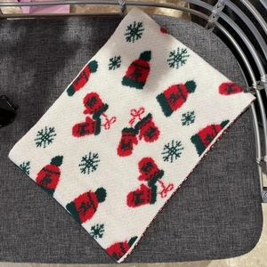 Detailed view of knitted Christmas scarf with festive red gloves and snowflake patterns