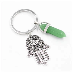 Detail of silver Hamsa Hand charm with green hexagonal crystal on a keychain