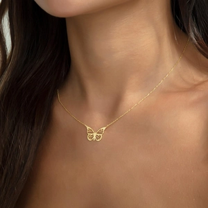 Gros plan d'un collier papillon en or 18 carats sur le cou avec une maille jante