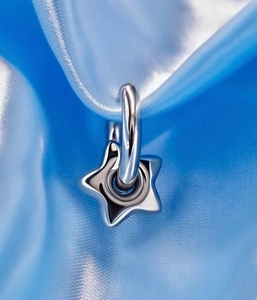 Macro detail of high-polished star-shaped pendant hanging on blue silk fabric texture