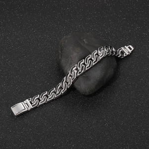 Close-up of punk style stainless steel bracelet with S-shaped links on black stone