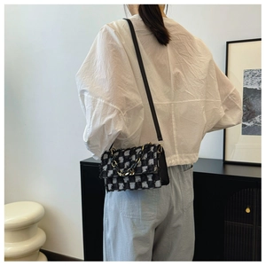 Détail du sac bandoulière en tweed à carreaux avec bords effilochés porté par un modèle