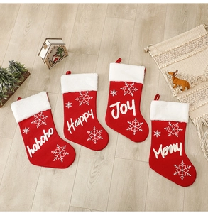 Detailed view of four red knitted Christmas stockings with snowflake patterns on wood floor