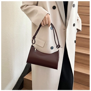 Detail of dark brown baguette bag featuring unique decorative knot on the strap