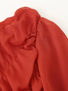 Detail shot of red ruched fabric texture with pleated folds for long sleeve dress