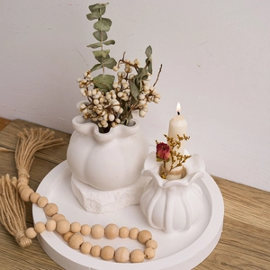 White ceramic flower vase set with ruffled edges and pumpkin texture on wooden table