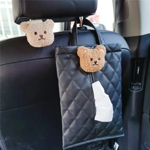Close-up of black quilted leather car tissue holder with brown plush bear on seat