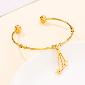 Detail view of gold moon and star charms on a polished titanium steel open bangle