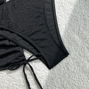 Detail der schwarzen strukturierten Bikini-Hose mit seitlichen Bindebändern