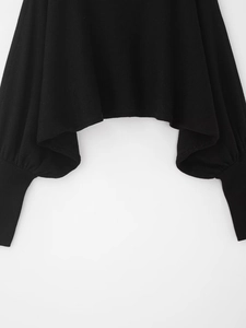 Detail of black knit sweater featuring ribbed cuffs and a unique irregular hemline