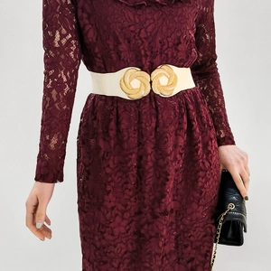 Detail of white elastic waist belt with textured gold double-ring buckle on red lace dress