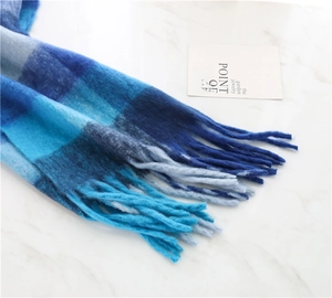 Close-up detail of blue checkered scarf featuring thick cashmere-like texture and soft fringes