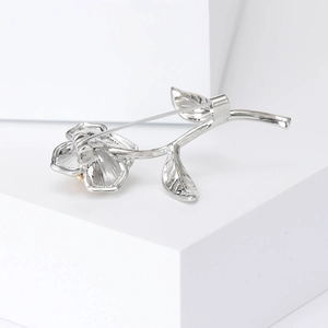 Elegant vintage silver and gold two-tone rose flower brooch on a white pedestal