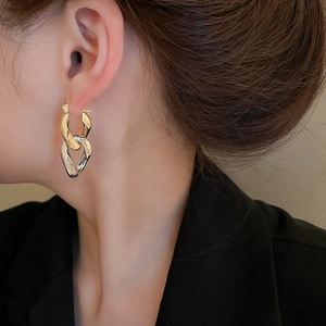 Détail des boucles d'oreilles chaînées or et argent portées par un mannequin avec style