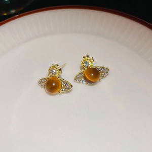 Macro detail of gold planet stud earrings with cat-eye stone and crystal accents