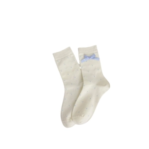 Chaussettes en tricot crème à pois bleus avec un ruban délicat sur fond blanc épuré