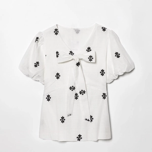 White puff sleeve dress with black floral embroidery and V-neck bow tie detail