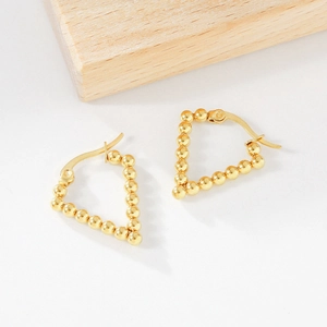 Detailed view of gold-plated beaded triangle hoop earrings on a light wooden background