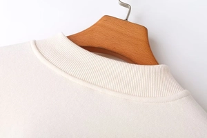 Close-up of a white sweatshirt's ribbed crew neck on a wooden hanger with clean details
