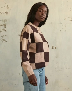 Side view of a cozy brown and beige checkerboard knit sweater on a model with jeans