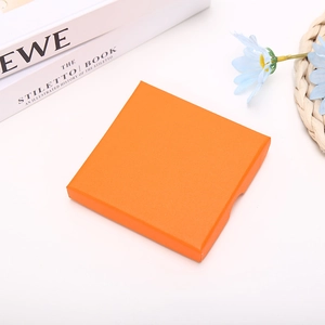 Detail of square orange jewelry gift box with textured matte finish on a clean background