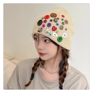 Detail of beige knit beanie featuring colorful heart and round novelty buttons