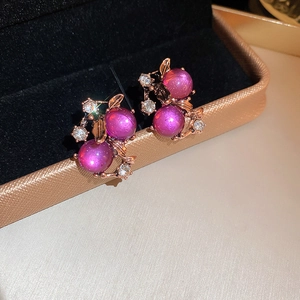 Detail of rose gold berry stud earrings featuring purple gems and white crystals