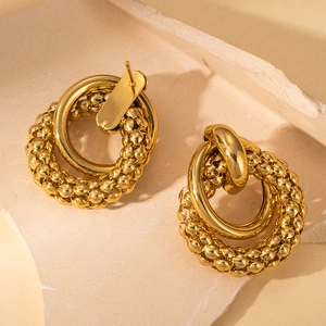 Detailed close-up of gold-plated double hoop earrings with smooth and beaded texture