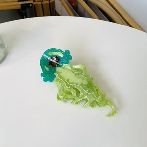 Detailed view of a green jellyfish hair claw clip made of semi-transparent acetate material