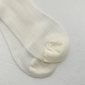 Detailed close-up of white ribbed knit ballet socks with high-quality seam details