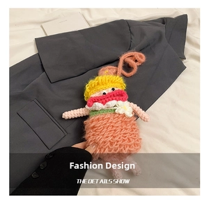 Detail showing pink handmade crochet doll bag with yellow hair and white flower accents