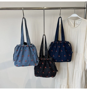 Detailed view of denim bucket bags with cherry embroidery in blue and grey tones