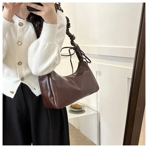 Close-up of dark brown cloud bag with glossy texture and ruched shoulder strap detail