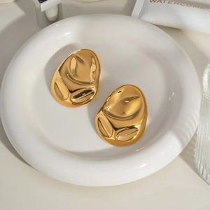 Detailed view of polished 18K gold-plated irregular geometric earrings on a tray