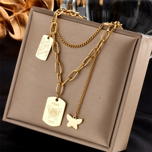 Close-up of gold layered chain necklace featuring butterfly pendant and engraved tags