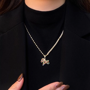 Detail of a half-pearl half-gold chain necklace with a colorful gemstone puppy pendant
